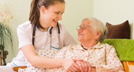 A female nurse visiting an elderly patient and holding her hands