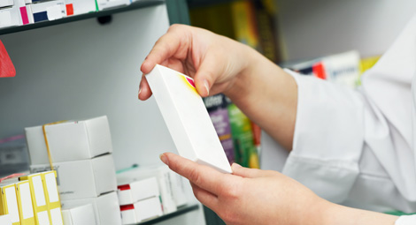 A pharmacist holding a packet of medication